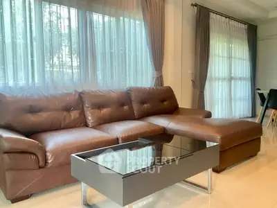 Spacious living room with elegant brown leather sofa and glass coffee table, perfect for relaxation.