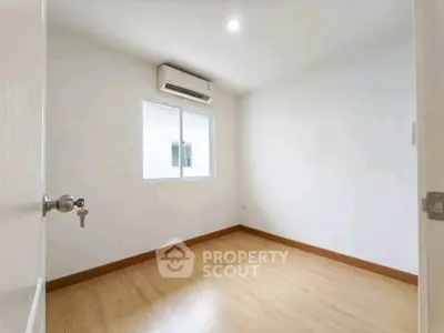 Spacious empty room with wooden flooring and air conditioning, perfect for customization.
