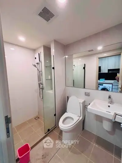 Modern bathroom with glass shower, sleek fixtures, and neutral tiles in a contemporary apartment.