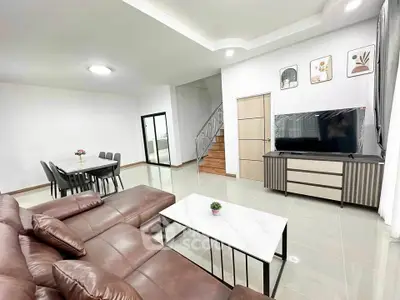 Spacious modern living room with leather sofa and large TV, perfect for family gatherings.