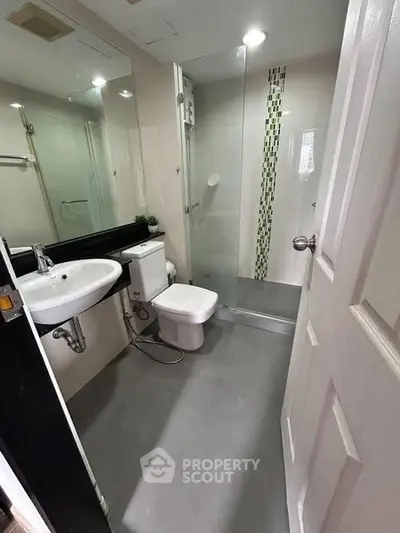 Modern bathroom with sleek design, featuring glass shower and contemporary fixtures.
