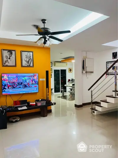 Modern living room with bright orange accent wall and sleek staircase