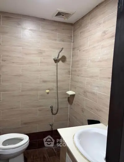 Modern bathroom with tiled walls and shower in a real estate property.