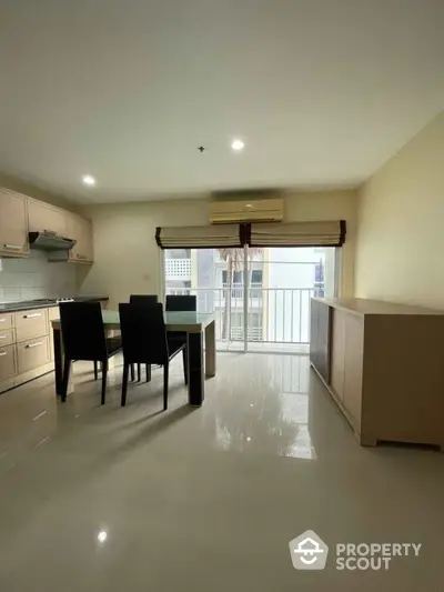 Modern kitchen with open layout and dining area, featuring sleek cabinetry and large windows.