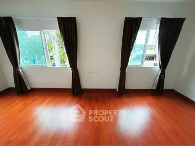 Spacious room with wooden flooring and large windows offering natural light and scenic views.