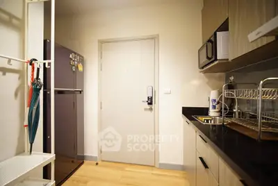 Modern kitchen with sleek cabinets, black countertops, and stainless steel appliances in a cozy apartment.
