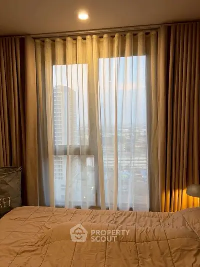 Cozy bedroom with city view through large window and elegant curtains.