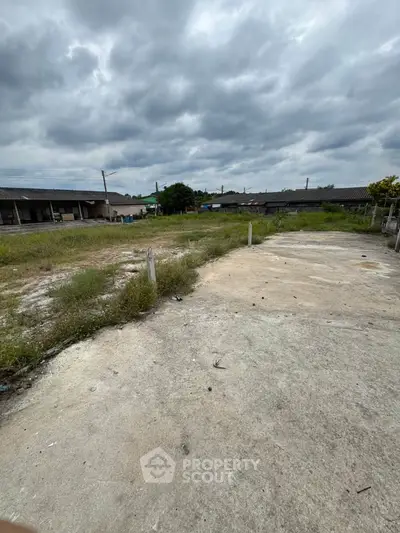 Spacious vacant land with potential for development under cloudy skies.