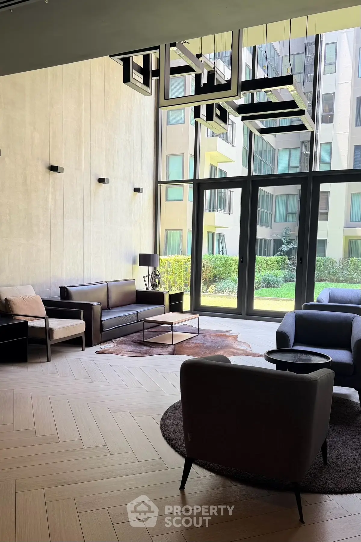 Modern living room with stylish furniture and large windows overlooking a garden view.
