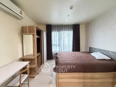 Spacious bedroom with modern furnishings and large window for natural light.
