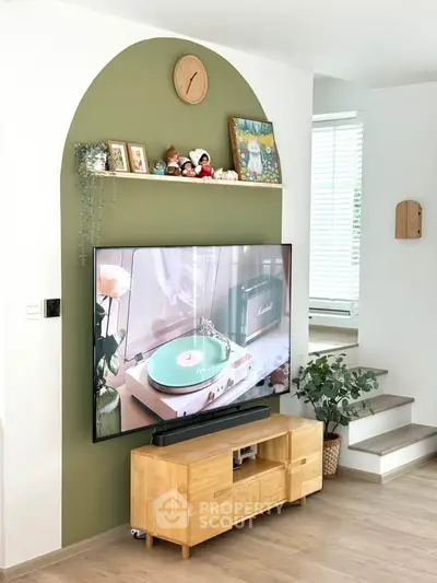 Stylish living room with modern TV setup and decorative shelf, featuring a cozy and inviting atmosphere.