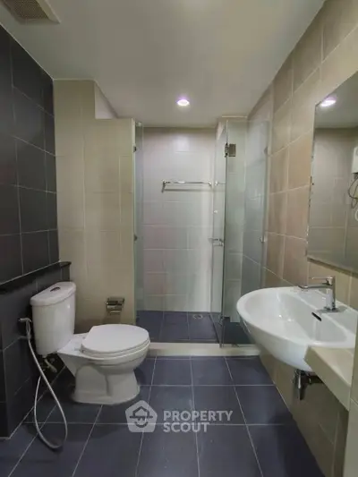 Modern bathroom with sleek design, featuring glass shower and contemporary fixtures.