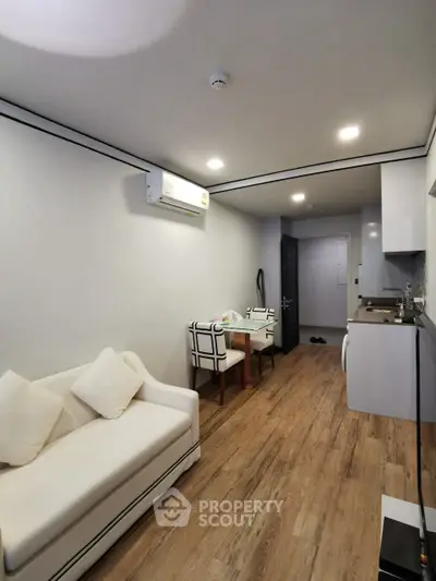 Modern apartment interior with cozy living area and compact kitchen, featuring stylish furniture and wooden flooring.