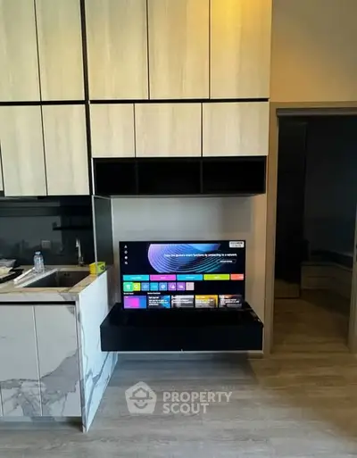 Modern kitchen with sleek cabinetry and built-in TV for stylish living.