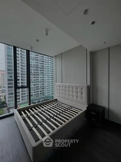 Modern bedroom with large windows and city view in a high-rise apartment.