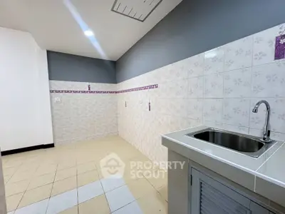 Spacious kitchen area with tiled walls and modern sink, ideal for culinary enthusiasts.