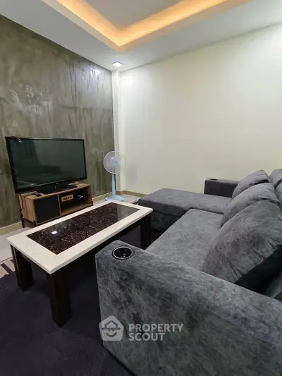 Cozy living room with modern gray sofa and flat-screen TV, perfect for relaxation.