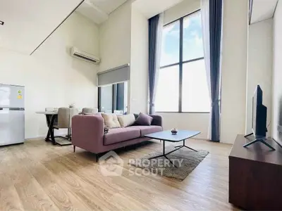 Spacious modern living room with high ceilings and large window, featuring stylish furniture and natural light.