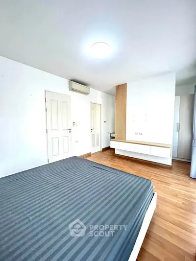 Spacious modern bedroom with wooden flooring and minimalist design