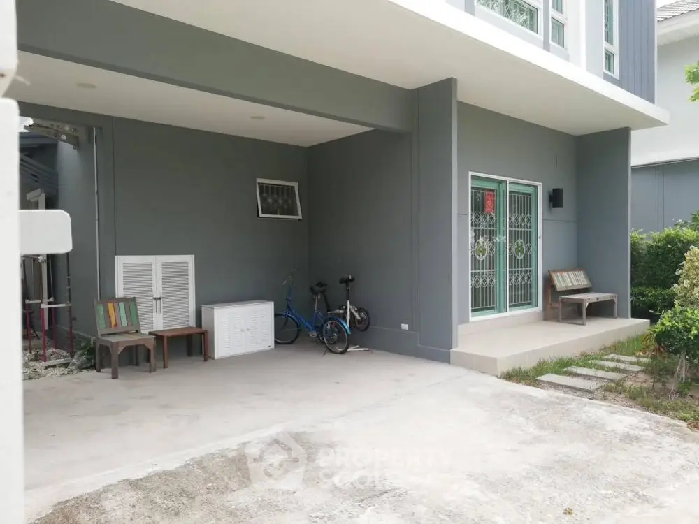 Modern house exterior with covered patio and bicycles, showcasing sleek design and inviting entryway.