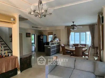 Spacious living room with modern decor and dining area, featuring elegant lighting and cozy seating.