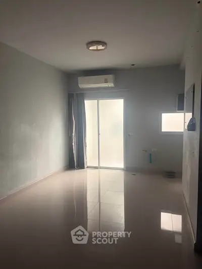 Spacious empty room with large window and air conditioning, ideal for customization.