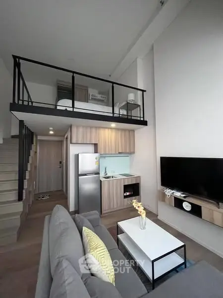 Modern loft apartment with high ceilings and mezzanine bedroom, featuring sleek kitchen and cozy living area.