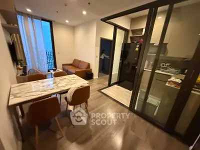 Modern apartment with open living and dining area, featuring sleek kitchen and stylish furnishings.