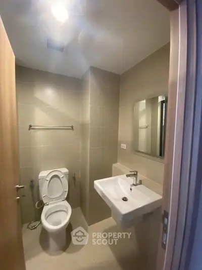 Modern bathroom with sleek fixtures and neutral tiles, featuring a toilet and sink.