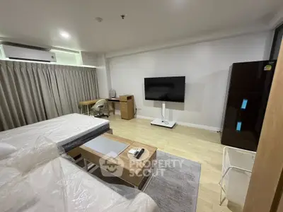 Spacious modern studio with sleek furniture and large TV, perfect for urban living.