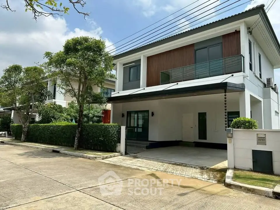 Modern two-story house with sleek design and spacious driveway in a suburban neighborhood.