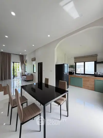 Spacious modern living room with open kitchen and dining area, featuring sleek furniture and abundant natural light.