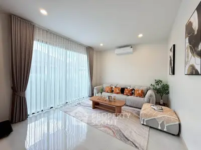 Modern living room with elegant decor, large window, and cozy seating area.