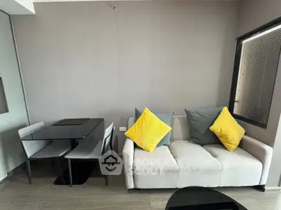 Modern living room with stylish sofa and dining area, featuring vibrant yellow cushions and sleek furniture.
