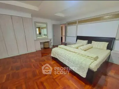 Spacious bedroom with elegant wooden flooring and modern furnishings