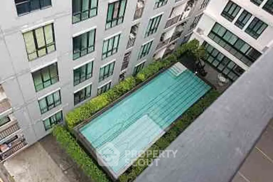 Modern apartment building with a rooftop pool and lush greenery.