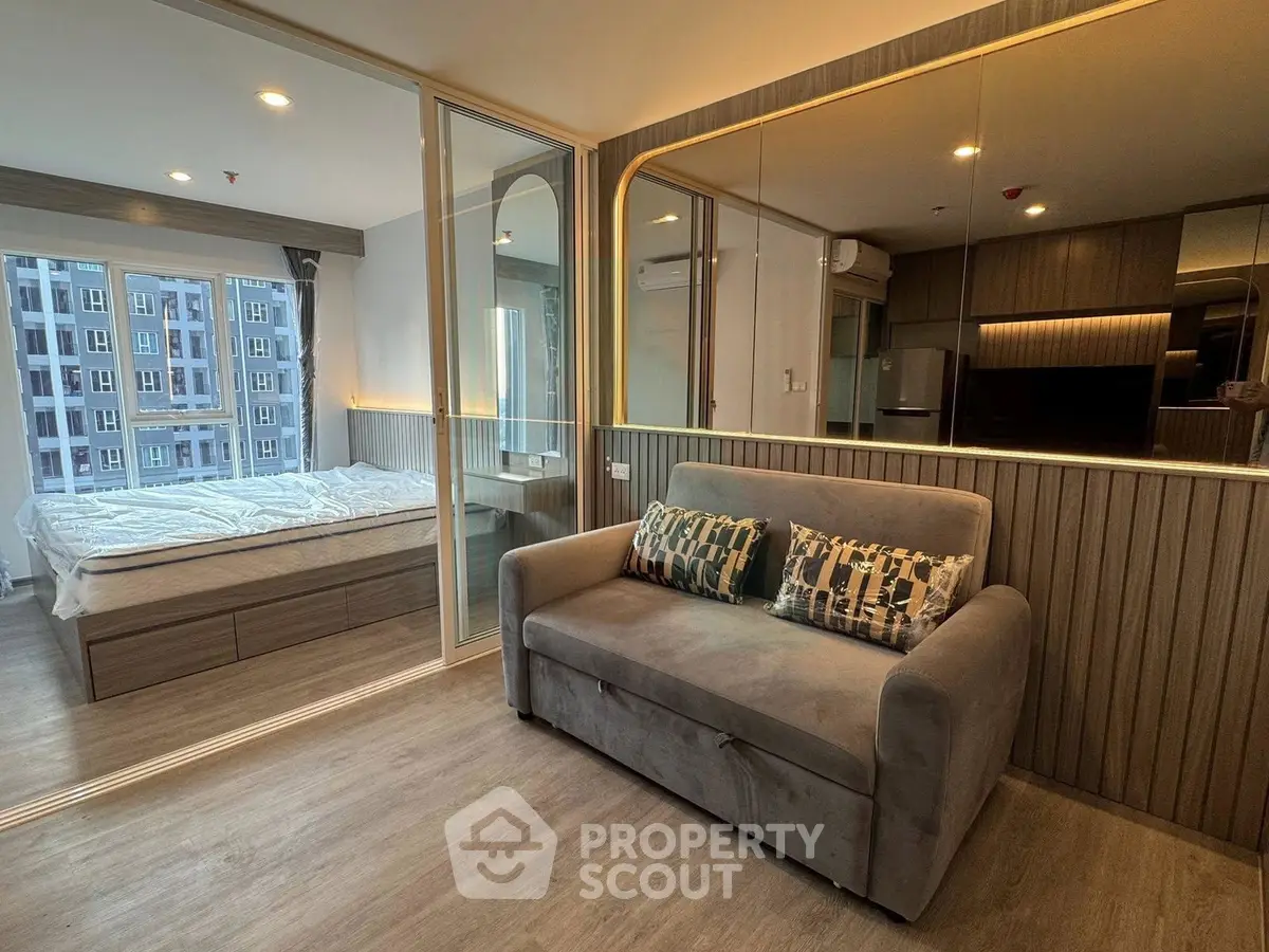Modern apartment interior with cozy living room and stylish bedroom separated by glass doors.
