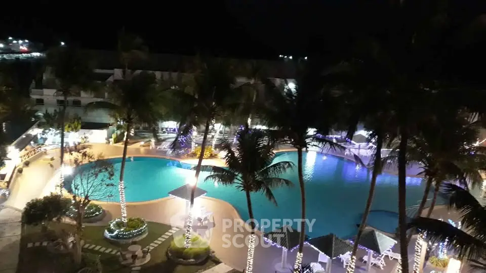 Luxurious resort-style pool area with palm trees and ambient lighting at night.