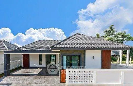 Modern single-story house with tiled roof and spacious driveway under a clear blue sky.