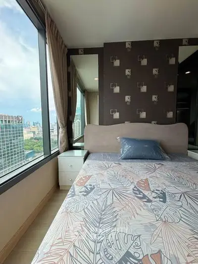 Stylish bedroom with city view, modern decor, and large windows in a high-rise apartment.