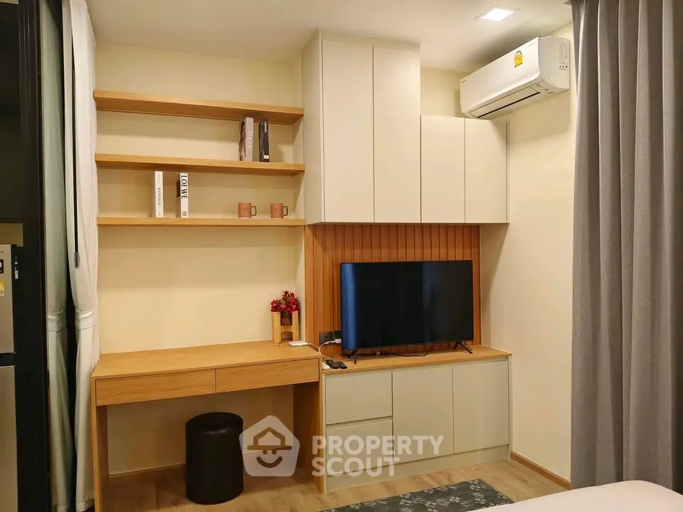 Modern living room with built-in shelves, TV, and air conditioning in cozy apartment.