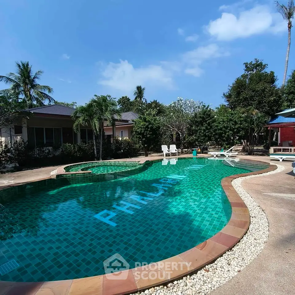 Luxurious outdoor pool area with lush greenery and clear blue skies, perfect for relaxation and leisure.