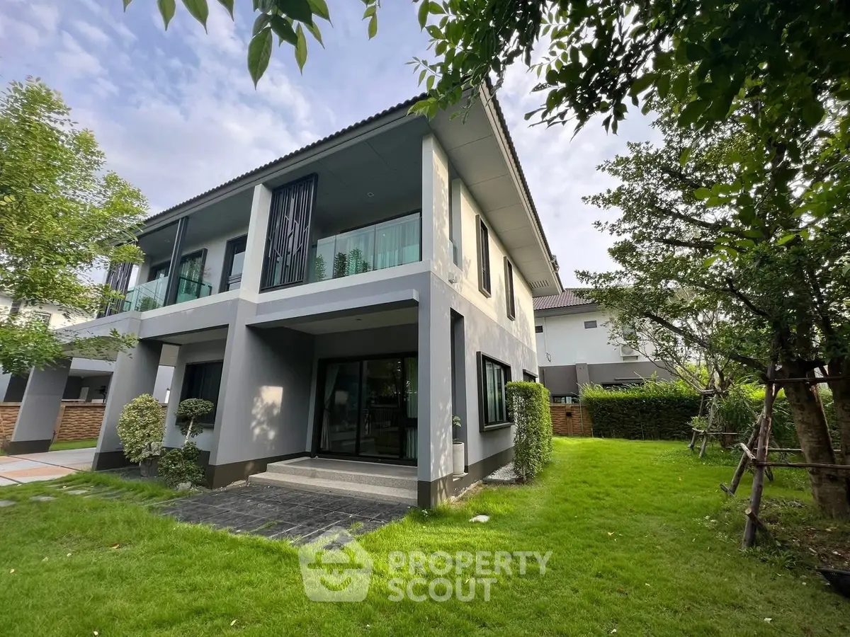 Modern two-story house with lush green garden and large windows