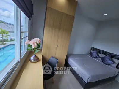 Modern bedroom with pool view, featuring sleek design and natural light.
