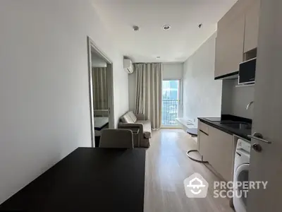 Modern apartment interior with sleek kitchen and cozy living area, featuring a washing machine and large window view.