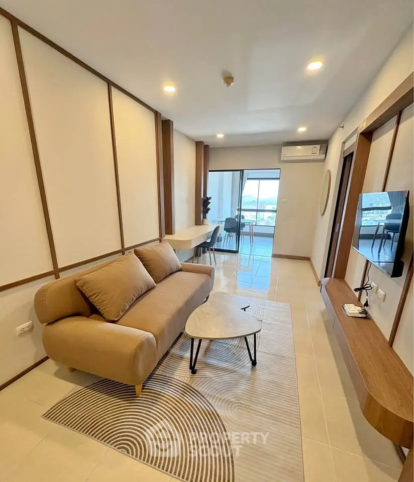 Modern living room with stylish decor and balcony view, featuring a cozy sofa and wall-mounted TV.