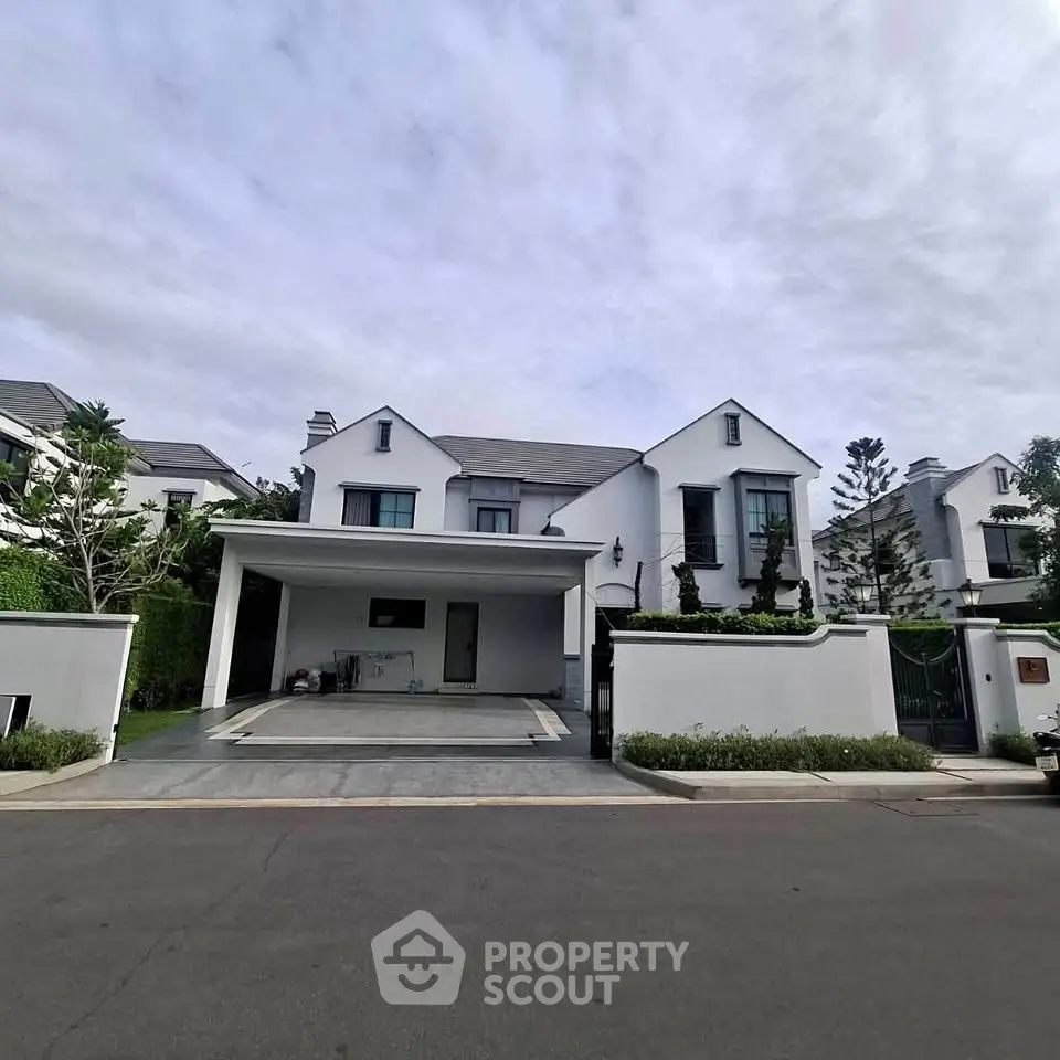 Elegant modern villa with spacious driveway and lush greenery in a serene neighborhood.
