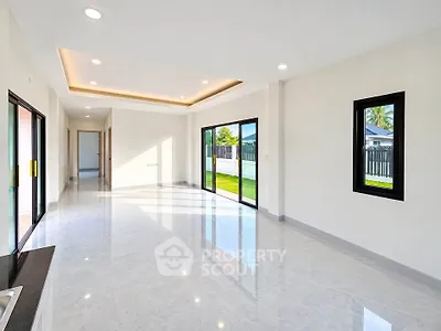 Spacious modern living room with large windows and garden view, perfect for family gatherings.