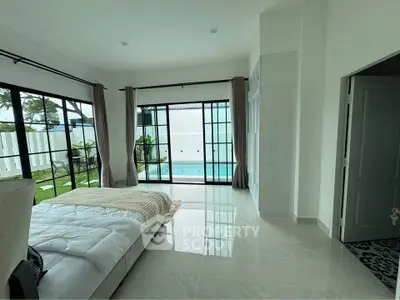 Spacious bedroom with pool view and large windows in modern home