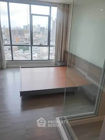 Spacious bedroom with large windows offering stunning city views in modern apartment.